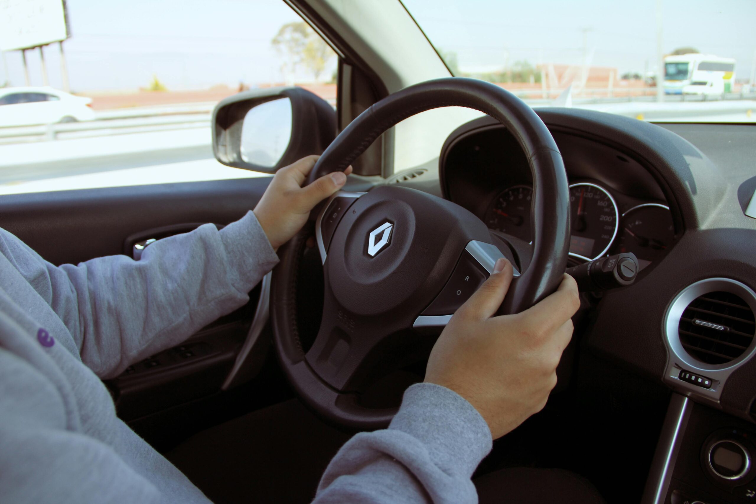Close-up of hands on steering wheel while driving through Mexico in daylight.
